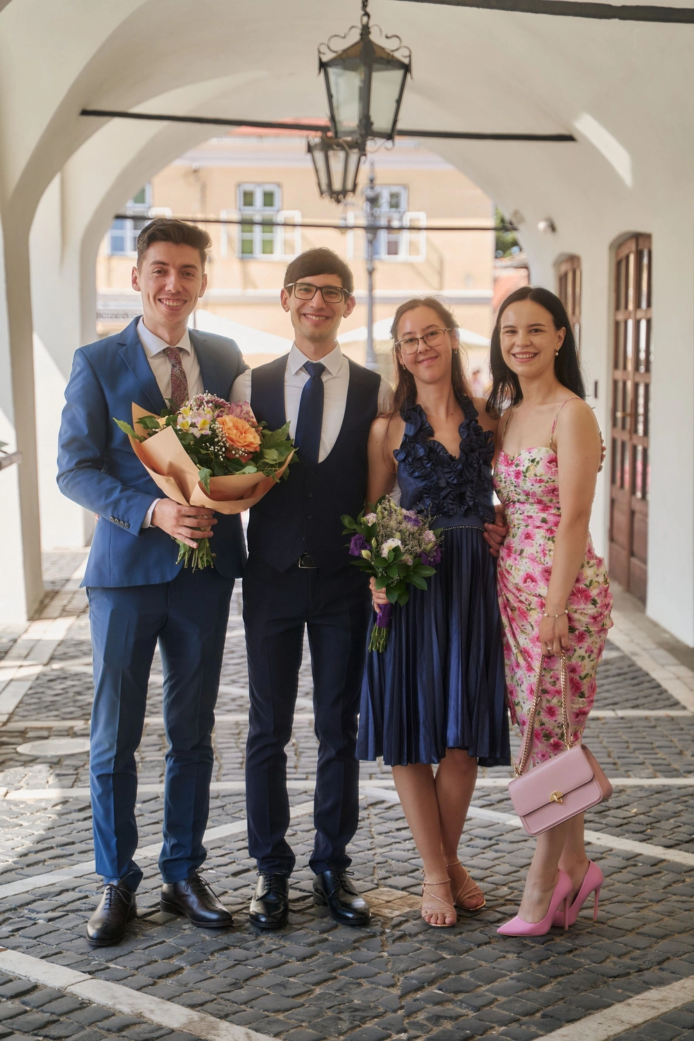 Ionuț Miclăuș, Horațiu Udrea, Luiza Udrea și Anamaria Miclăuș, de la stânga la dreapta, în picioare, zâmbind, sub arcadele unei clădiri vechi din Sibiu